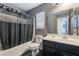 Bathroom with a shower-tub combo, gray and white shower curtain, single sink vanity, and a large mirror at 58 Desert Sunflower Cir, Henderson, NV 89002