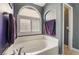 Modern bathroom with a soaking tub beneath an arch window with wood shutters at 58 Desert Sunflower Cir, Henderson, NV 89002