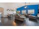 Open-concept living room with a gray sectional sofa, hardwood floors, and dining area with modern lighting at 58 Desert Sunflower Cir, Henderson, NV 89002