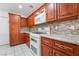 This kitchen features wooden cabinetry, updated appliances, and granite countertops at 60 Reyburn Dr, Henderson, NV 89074