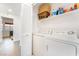 Bright laundry room featuring a washer, dryer, storage shelf, and white wood-look flooring at 60 Reyburn Dr, Henderson, NV 89074