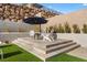 Backyard patio area with a fire pit, seating, lush landscaping, and terraced retaining wall at 733 Aberdeen Tartan St, Las Vegas, NV 89138