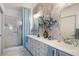 Bathroom features a double sink vanity with stone textured wall and glass door shower at 7505 Chaffinch St, North Las Vegas, NV 89084