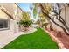 Private backyard with lush green grass, mature trees, and a stone-paved walkway to the pool at 7840 Red Leaf Dr, Las Vegas, NV 89131