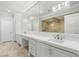 This bathroom boasts a dual sink vanity, stone floors, a large mirror, and an elegant chandelier at 9101 Alta Dr # 103, Las Vegas, NV 89145