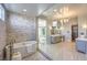 An elegant bathroom featuring a soaking tub, double vanity, and glass-enclosed shower at 11110 Mount Cass St, Las Vegas, NV 89141