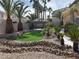 Landscaped backyard featuring tropical trees, artificial grass, and a shaded tiki hut with a serving bar at 11118 Scotscraig Ct, Las Vegas, NV 89141