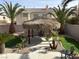 Landscaped backyard featuring an outdoor tiki hut, palm trees, and desert landscaping at 11118 Scotscraig Ct, Las Vegas, NV 89141