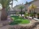 Landscaped backyard featuring tropical trees, artificial grass, and a shaded tiki hut with a serving bar at 11118 Scotscraig Ct, Las Vegas, NV 89141