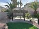 A backyard gazebo with a tiki roof and a stone bar top, surrounded by turf and desert landscaping at 11118 Scotscraig Ct, Las Vegas, NV 89141
