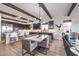 Open kitchen and dining area with stainless steel appliances, a island, and dark wood ceiling beams at 56 Tatahatso Point St, Henderson, NV 89011