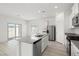 Modern kitchen features stainless appliances, white cabinets, stone countertops, and island with sink at 6737 Violet Cascade Ave, Las Vegas, NV 89156