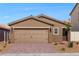 A single-story home features a tan exterior, brick driveway, and a two-car garage at 6749 Violet Cascade Ave, Las Vegas, NV 89156