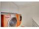 Orange washer and dryer setup with cabinets above in a well-lit laundry area at 7771 Pleasant Slopes Ct, Las Vegas, NV 89131