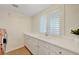 Bright laundry room featuring built-in cabinets, utility sink, and plantation shutters at 7771 Pleasant Slopes Ct, Las Vegas, NV 89131