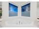 A soaking tub with chrome fixtures sits beneath obscured windows offering light and privacy at 800 Loch Katrine Ave, Henderson, NV 89012