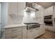 Close up of a modern range and stainless steel hood with white cabinets and backsplash at 800 Loch Katrine Ave, Henderson, NV 89012