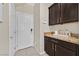 Mud room area with dark cabinets, granite countertop, and access to the garage and pantry at 9413 Aggie Ct, Las Vegas, NV 89148