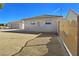 A side view of the house, highlighting a metal gate, beige stucco, and a spacious, dirt-covered side yard at 1981 Labrador St, Pahrump, NV 89048