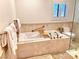 Bright bathroom features a soaking tub with travertine tile and accent flowers for a spa-like feel at 3999 Delos Dr, Las Vegas, NV 89103