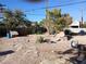 View of the backyard featuring dirt ground, stone pavers, a wooden fence and scattered bushes at 4200 Coran Ln, Las Vegas, NV 89108