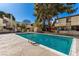 Community pool with pool furniture, enclosed by black fencing, and mature trees at 5015 Spencer St # C, Las Vegas, NV 89119