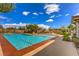 Relaxing community pool surrounded by lounge chairs, green landscaping, and a bright blue sky with fluffy clouds at 7735 Sugarloaf Peak St, Las Vegas, NV 89166