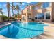 Inviting backyard pool with tanning ledge, lush palm trees and outdoor seating area, perfect for relaxing and entertaining at 8225 Taos Paseo Ave, Las Vegas, NV 89128