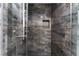 Modern shower with dark marble-like tile, sleek fixtures, and convenient shelving at 8348 Brittany Harbor Dr, Las Vegas, NV 89128