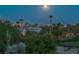 Exterior view of a luxury home at night with a full moon and surrounding desert landscape and golf course at 11473 Glowing Sunset Ln, Las Vegas, NV 89135