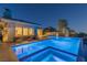Luxurious backyard pool and spa illuminated at dusk, with lounge chairs and covered patio at 11473 Glowing Sunset Ln, Las Vegas, NV 89135