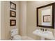 Elegant powder room with a pedestal sink, decorative mirror, and framed artwork at 11473 Glowing Sunset Ln, Las Vegas, NV 89135