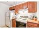 Functional kitchen featuring light appliances, warm wood cabinets and a bright white refrigerator at 1381 E University Ave # 301, Las Vegas, NV 89119