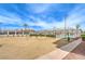 Common area with sparse landscaping and tennis courts behind the fence under a sunny blue sky at 3790 Shirebrook Dr # 167, Las Vegas, NV 89115