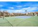 Full tennis court surrounded by fenced-in condos, sparse landscaping, and street lights under a sunny blue sky at 3790 Shirebrook Dr # 167, Las Vegas, NV 89115