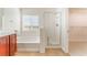 Bathroom featuring a shower and a bathtub, a large window, and cherry wood cabinets at 4740 Killington St, Las Vegas, NV 89129
