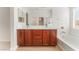 Bathroom featuring double sinks, a bathtub, and a vanity with cherry wood cabinets at 4740 Killington St, Las Vegas, NV 89129