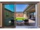 View of backyard featuring brick patio, artificial grass, landscaping, and seating area from inside the home at 6801 Steel Mist St, Las Vegas, NV 89148
