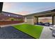 Well-maintained backyard with artificial grass, patio seating, and a landscape wall, perfect for relaxation at 6801 Steel Mist St, Las Vegas, NV 89148