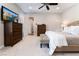 Carpeted bedroom features ceiling fan, TV, ensuite bathroom and a tufted headboard bed at 6801 Steel Mist St, Las Vegas, NV 89148