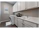 Well-lit laundry room featuring modern washer and dryer, white cabinetry, countertop, and sink for convenience at 6801 Steel Mist St, Las Vegas, NV 89148