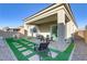 Lush backyard featuring a covered patio, outdoor seating, and manicured artificial grass at 8729 Marcana St, Las Vegas, NV 89166