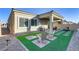 Green backyard featuring a covered patio, outdoor seating, and artificial grass at 8729 Marcana St, Las Vegas, NV 89166