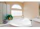 Bright bathroom featuring a large soaking tub beneath an arched window at 10608 Medicine Bow St, Las Vegas, NV 89183