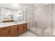 Bright bathroom featuring wood cabinets, double sinks, quartz countertops, and a glass-enclosed walk-in shower with a bench at 2486 Veronella St, Henderson, NV 89044