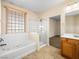 Bathroom with soaking tub, glass shower, wood cabinets, and bright lighting at 6360 Bullring Ln, Las Vegas, NV 89130