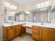 Bright bathroom featuring dual sinks, spacious counters, wooden cabinetry, and large mirrors for a luxurious feel at 6360 Bullring Ln, Las Vegas, NV 89130