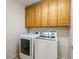 Bright laundry room featuring modern white washer and dryer, and storage cabinets above at 6360 Bullring Ln, Las Vegas, NV 89130