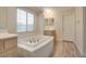 Bright bathroom features a large soaking tub, wood-look floors, and a window letting in natural light at 6632 Biltmore Garden St, Las Vegas, NV 89149