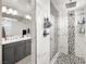 Stylish bathroom featuring a glass enclosed shower with unique tile accents, gray cabinets, and a large mirror at 70 Pikiariki Ct, Las Vegas, NV 89183